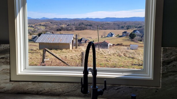 A bathroom with a window offering a view of a rural landscape, including fields and distant mountains. - Thomas Cottage at Angel Acres (Fincastle)