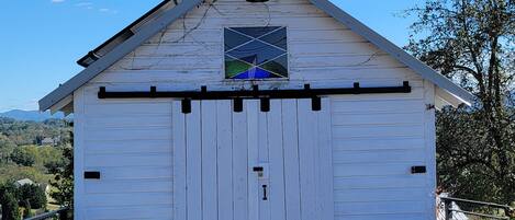 A white barn with a triangular roof and a stained glass window.