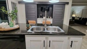 Una cocina moderna con un lavamanos doble, armarios blancos y una encimera.