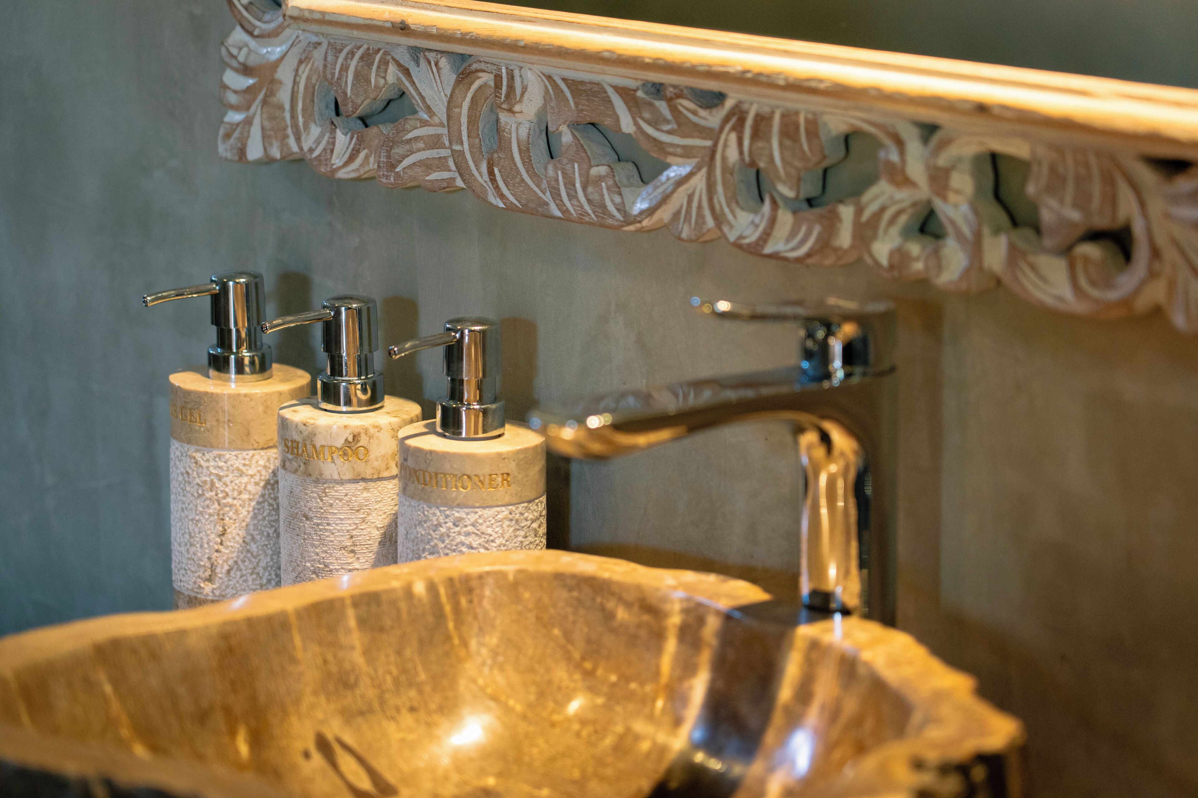 A bathroom with a large, ornate sink and three bottles labeled "SHAMPOO," "SHAMPOO," and "SHAMPOO."