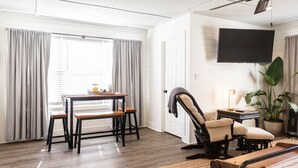 Una habitación con una cama, un escritorio, una silla, un televisor y una ventana con cortinas.