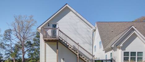 Une maison à deux étages avec un porche à l’avant, un escalier menant au deuxième étage et une cour clôturée.