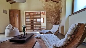 Ein Zimmer mit einer Holzcouch, einem Sitzsack, einem kleinen Tisch mit einer Vase und einer Holzkommode.