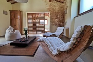 A room with a wooden sofa, a bean bag, a small table with a vase, and a wooden cabinet. - Villa Fornace by MMega (Lisciano Niccone)