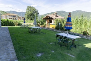 A well-maintained outdoor dining area with tables and chairs, surrounded by greenery and a stone wall. - Villa Fornace by MMega (Lisciano Niccone)
