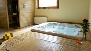 Ein Saunaraum mit Holzboden, einer Whirlwanne und einem Fenster.