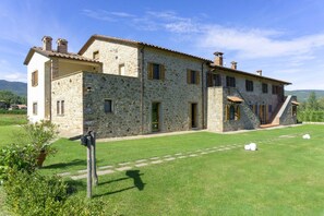 A stone building with multiple windows and a well-maintained lawn.