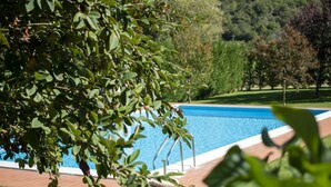 Ein Swimmingpool mit klarem, blauem Wasser, umgeben von einer Backsteindecke und grünem Rasen.