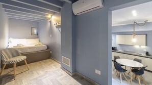 A modern room with a bed, bedside table, chair, and a small kitchenette area with a dining table and chairs. - San Luca Apartments - Fieschi by Wonderful Italy (Genoa)