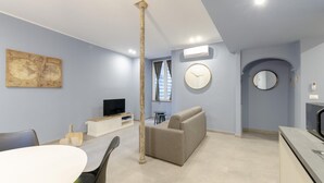 A modern living room with a sofa, a TV, a dining table, and a large world map on the wall. - San Luca Apartments - Fieschi by Wonderful Italy (Genoa)