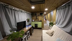 A cozy living area with a sofa, a TV, and a dining table with chairs. - House on a BUS by the river (Florianópolis)