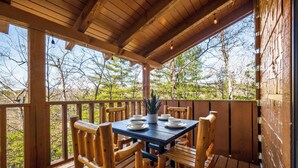 A wooden deck with a table set for four, surrounded by wooden chairs, overlooking a forested area. - King Suites, Privacy, A+ Location, Hot Tub, Games (Sevierville)
