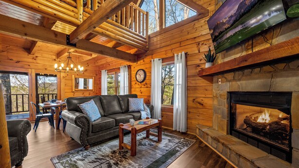 A log cabin interior with a fireplace, wooden furniture, and a dining area. - King Suites, Privacy, A+ Location, Hot Tub, Games (Sevierville)
