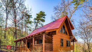 A wooden cabin with a red roof, surrounded by trees. - King Suites, Privacy, A+ Location, Hot Tub, Games (Sevierville)