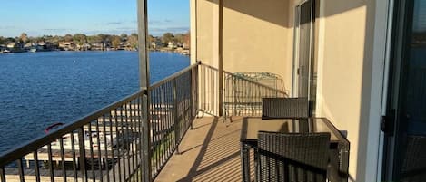 Varanda com vista para um lago, uma mesa e cadeiras.