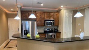 A kitchen with wooden cabinets, stainless steel appliances, and a granite countertop. - Sunset Lake House 304 (Willis)