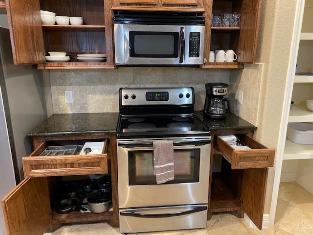 A compact kitchen with a microwave, stove, and coffee maker.