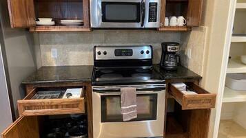 A compact kitchen with a microwave, stove, and coffee maker.