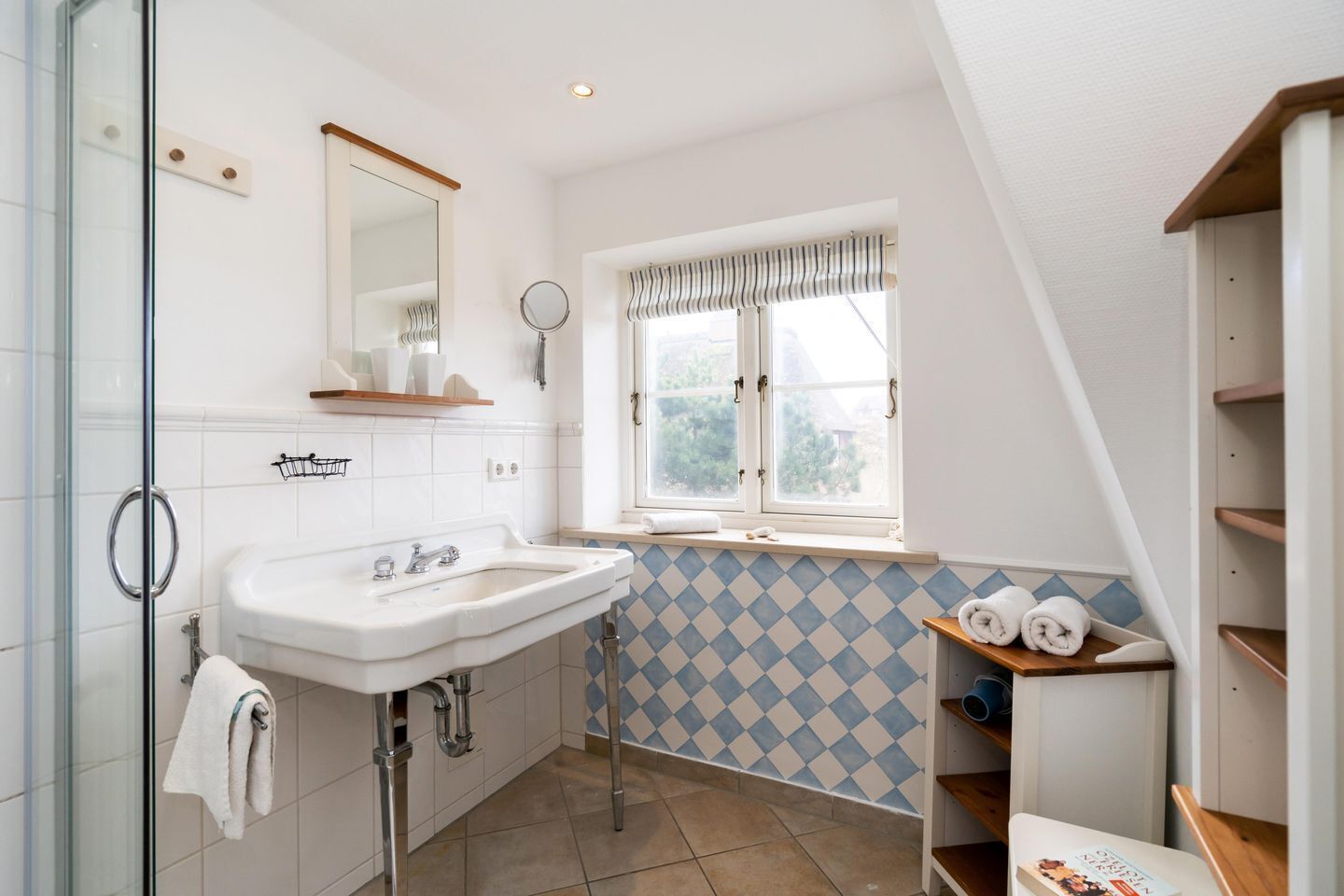 A modern bathroom with a white sink, mirror, and window with curtains.
