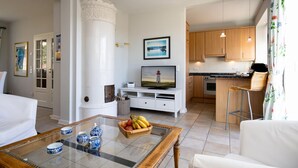 Una sala de estar con chimenea, televisor y una cocina con armarios de madera.