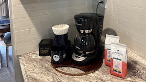 Un comptoir de cuisine avec une machine à café, des tasses à café et des grains de café.