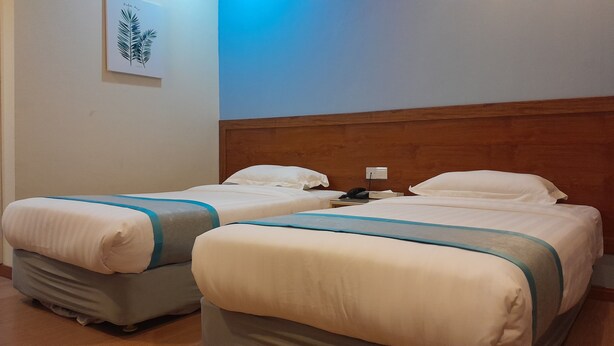 Two single beds with wooden headboards, white bedding, and a bedside table with a phone. - TD CAPITAL HOTEL (Kota Kinabalu)