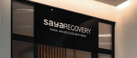 Een bordje voor 'SayaRecovery' met diensten zoals sauna, jacuzzi en ijsbadruimte.