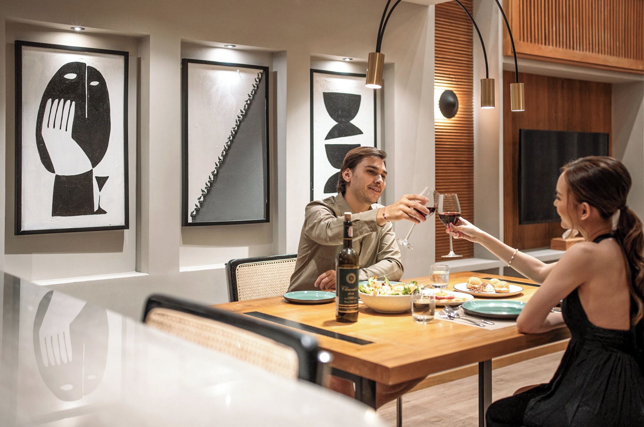 A dining area with a wooden table, chairs, a bottle, and glasses.