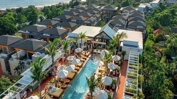 Un resort con piscina, tumbonas y vista al océano.
