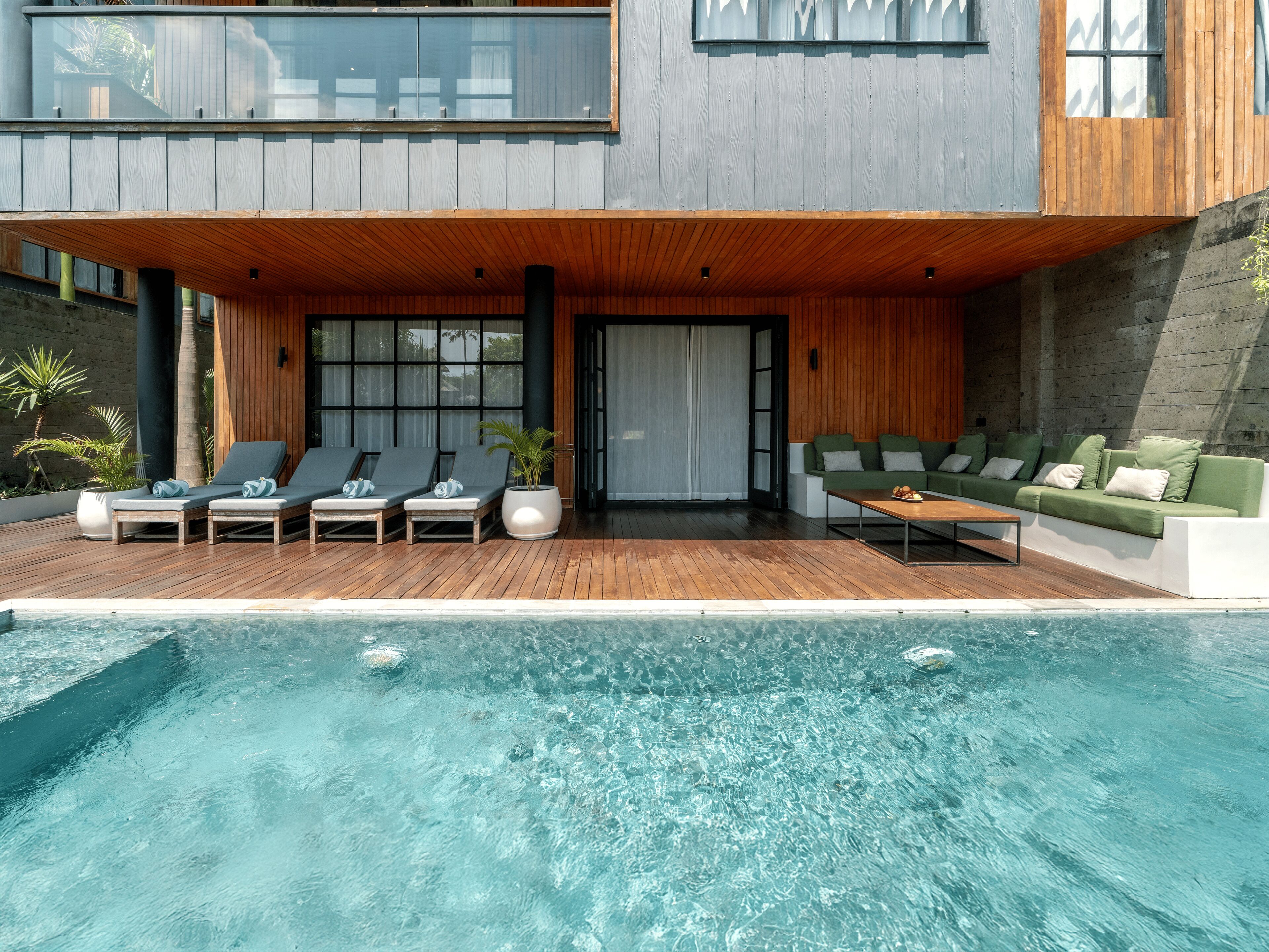 Una casa moderna con piscina, terraza de madera y zona de estar al aire libre.
