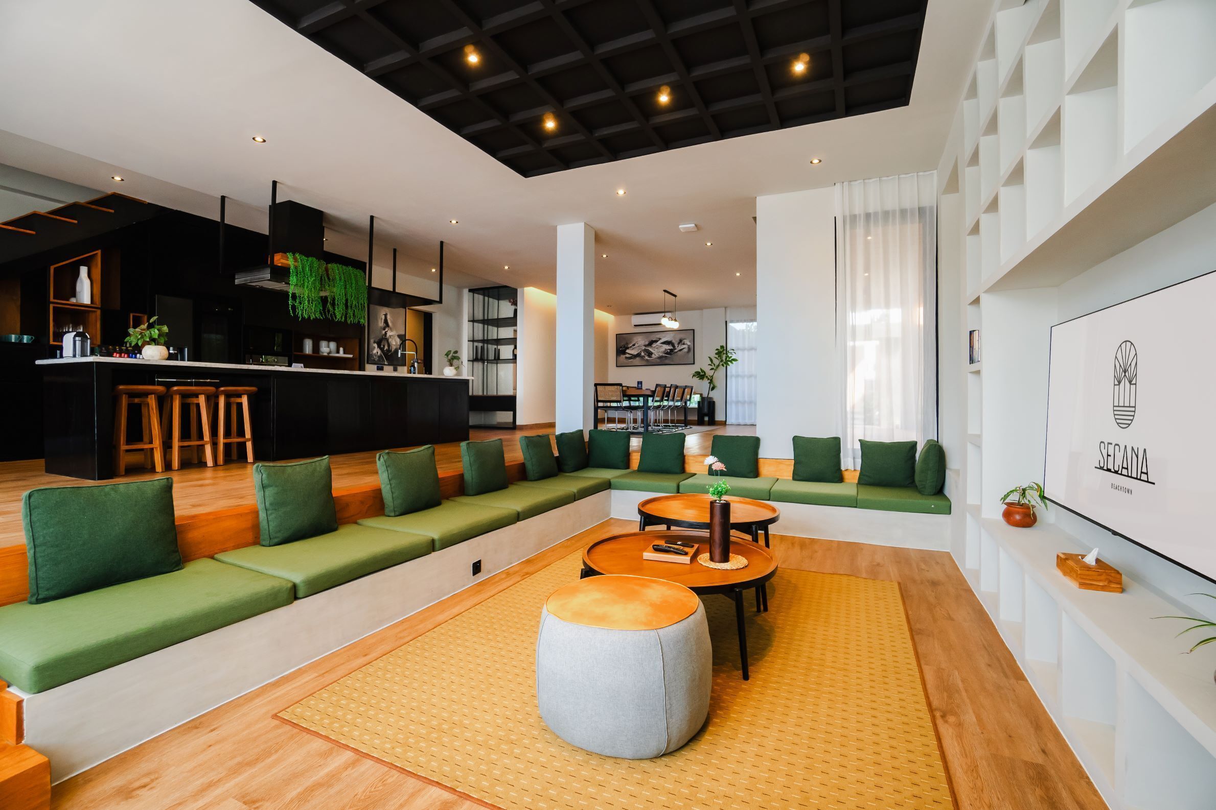 A modern lounge area with green seating, a bar, and a large artwork on the wall.