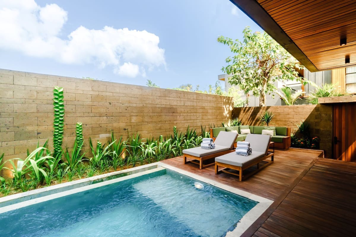 Un área de piscina con sillones de descanso y una terraza de madera.