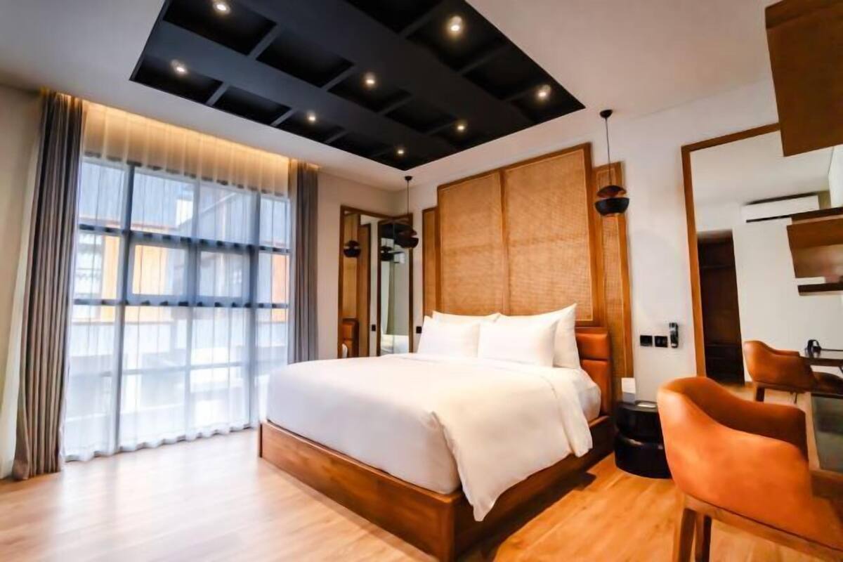 Una habitación de hotel moderna con una cama grande, cabecero de madera y vistas a la ciudad.