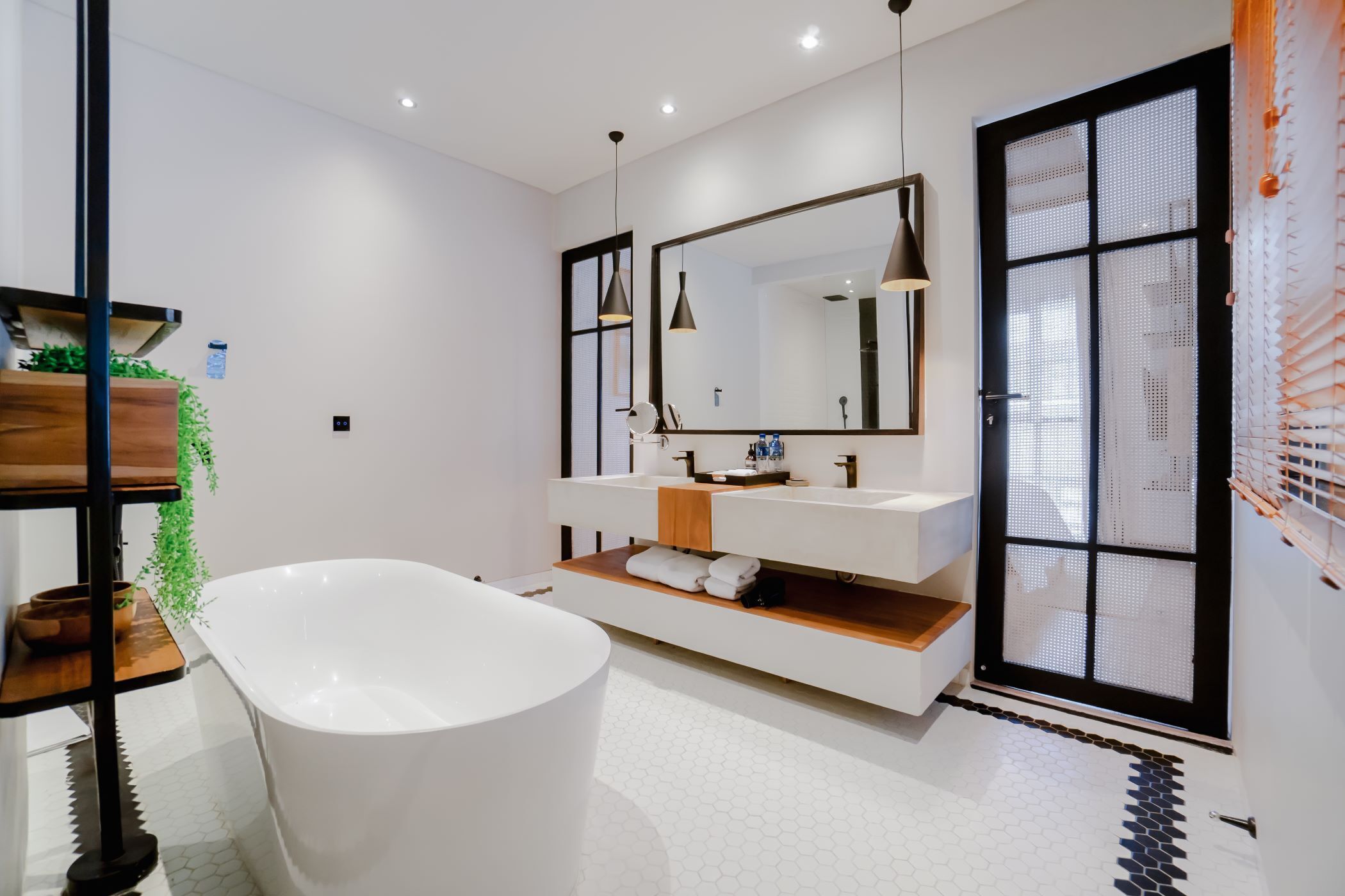 Ein modernes Badezimmer mit freistehender Badewanne, einem großen Spiegel und einem Holzwaschtisch mit Waschbecken.