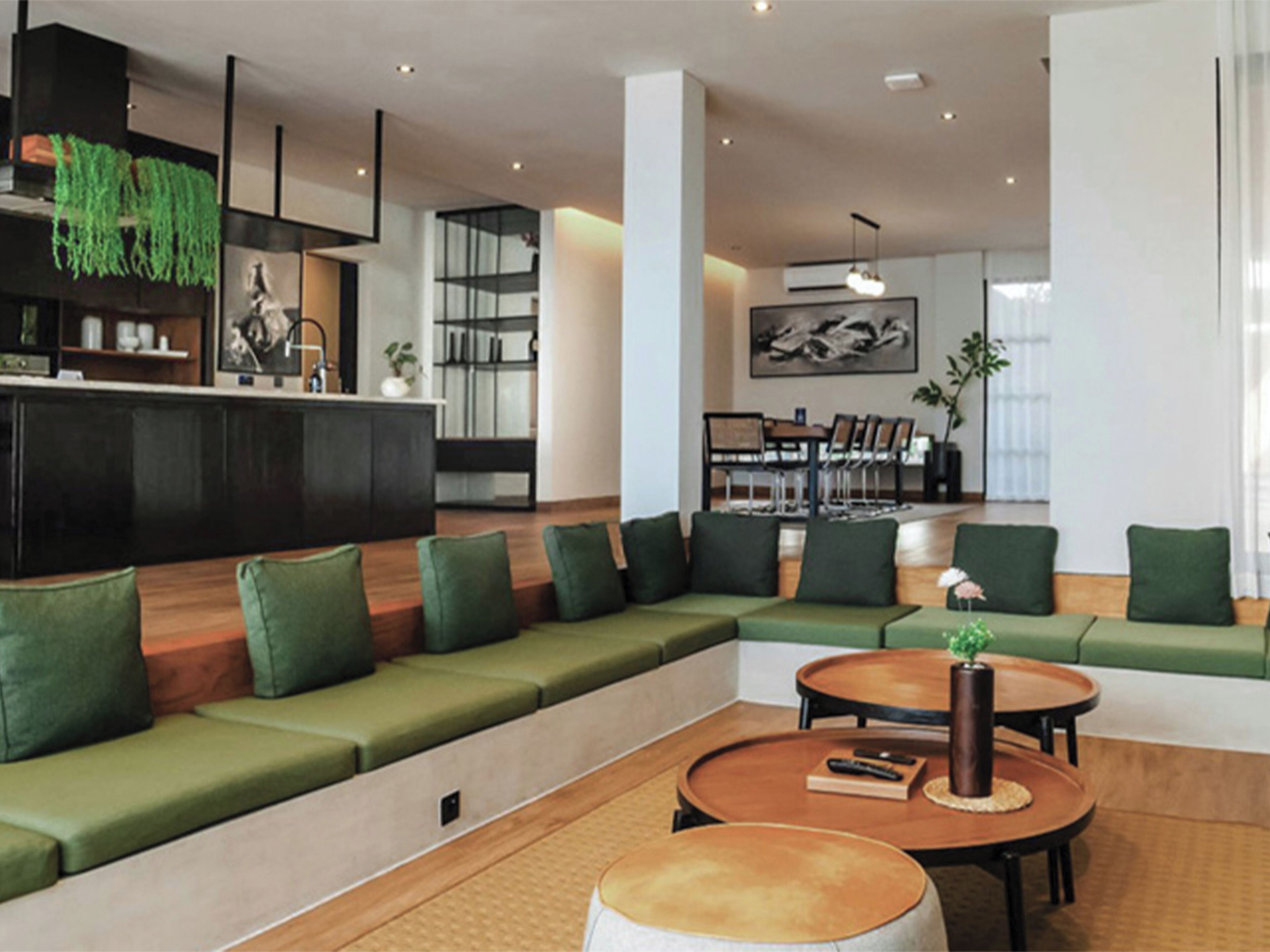 A modern hotel lobby with a sectional sofa, round tables, and a dining area.