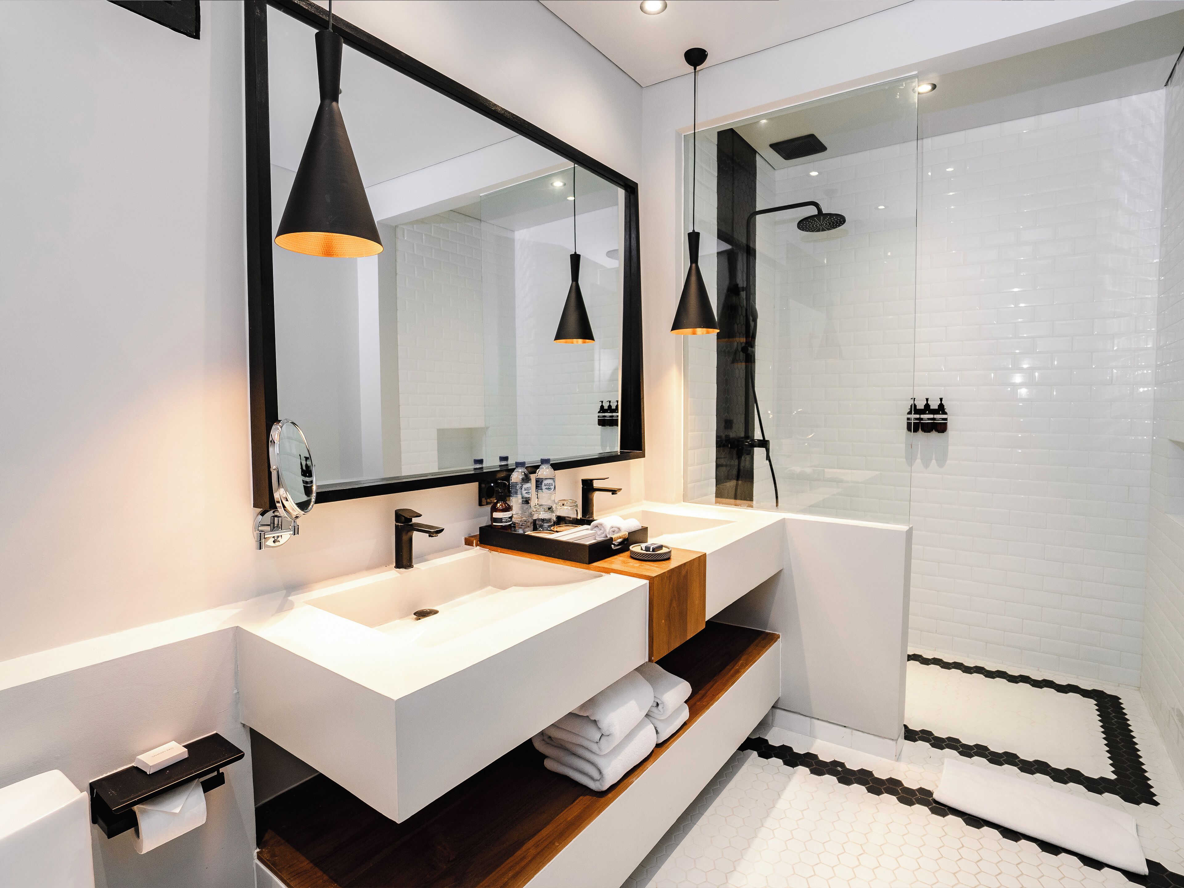 Ein modernes Badezimmer mit zwei Waschbecken, einem großen Spiegel und einer Duschkabine.
