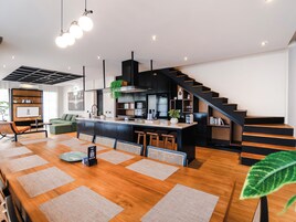 Una cocina moderna con una isla central, muebles negros y una escalera que sube a otro nivel.