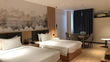 A hotel room with two beds, a desk, and a dining area.