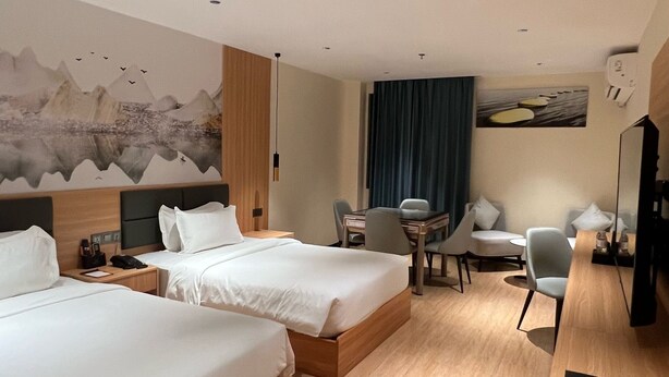 A hotel room with two beds, a desk, a chair, a dining table, and a TV. - Jinjiang Star Hotel (Pasay)
