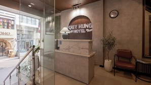 Una mesa de recepción con un reloj y un cartel para el Hotel Quy Hung.
