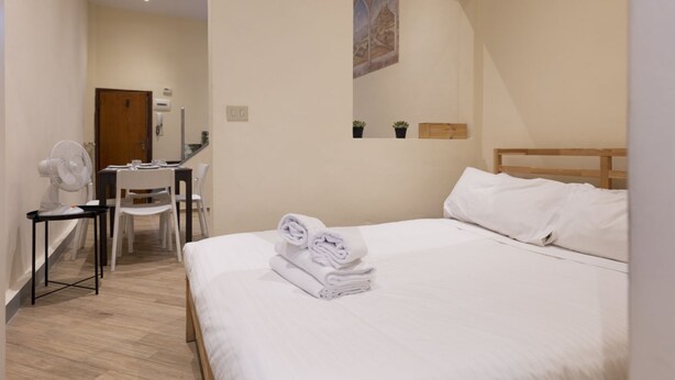 A hotel room with a bed, a desk with a chair, a fan, and a painting on the wall. - Chianti's Inn Sangiovese (Firenze)