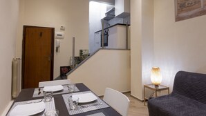 A dining area with a table set for four, a staircase leading to a kitchen, and a lamp on a side table. - Chianti's Inn Sangiovese (Firenze)