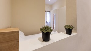 A hallway with a white bench and two potted plants on a shelf. - Chianti's Inn Sangiovese (Firenze)