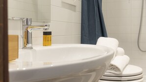 A bathroom with a white sink, a towel rack with folded towels, and a shower area with a blue curtain. - Chianti's Inn Malvasia (Firenze)