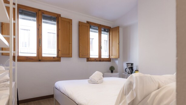 A bedroom with a bed, wooden windows, a bedside table with a plant, and a coffee maker. - Chianti's Inn Trebbiano (Firenze)