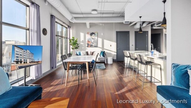 A modern apartment with a dining area, kitchen, and a large window. - Cityscape Apartment w/ Terrace - Leonard Luxury Apartment (Muskegon)
