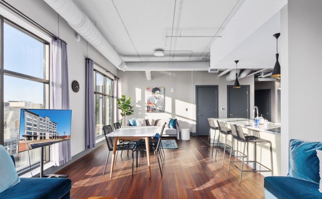 A modern apartment with a dining area, kitchen, and a large window.