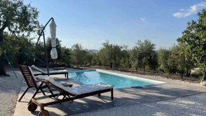 Una piscina con sillones de descanso y una sombrilla.