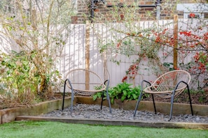 Relax in a serene garden setting with two comfortable chairs on a gravel path surrounded by lush greenery.