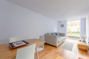 Relax in this serene living space with a comfortable sofa, dining table, and large window offering a view of the outdoors.